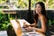 Young 20s Asian woman looking at camera while wearing a protective mask with laptop, mobile phone, and notebook for