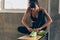 Young active Caucasian sporty woman tying shoelace on green shoes in gym