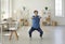 Young active and energetic businessman squatting doing sports training in his home office.