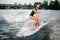 Young active girl in cap riding on the wakesurf