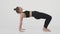 Young active lady practicing yoga over white studio background, swinging forward and backward on her hands