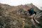 Young active male hiking in mountains with travel backpack. Traveler bearded man trekking and mountaineering during his journey