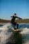 young active man energetically balancing on a wave on a wakesurf board