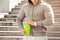 Young active man is going to drink looking at his watch, schedule, outdoors. Handsome muscular male holding shaker, drinking water