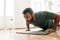 Young active man looking focused, exercising, doing push ups during morning workout at home. Sport, healthy lifestyle