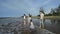 Young active parents with three daughters enjoying barefoot in water on beach