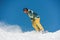 Young active snowboarder in bright sportswear riding down a mountain slope