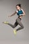 Young active sporty woman dressed in sportswear jumping in studio.