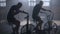 Young active two man spinning a air bike in gym with trainers. Two male training on air bike with friends encouraging.