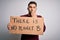 Young activist man holding protest banner for climate change and environment change cover mouth with hand shocked with shame for