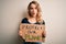 Young activist woman asking for environment holding banner with protect planet message scared in shock with a surprise face,