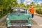 Young adolescent standing beside a classic car