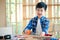 Young adorable Asia boy wearing shirt and T-shirt and sawing wood with a toy saw in the classroom. The cute kid was very happy and