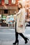 Young adul beautiful woman walking on city street wearing casual street style autumn outfit with grey jacket