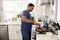 Young adult African American  man standing in the kitchen cooking on the hob, using a spatula and frying pan, side view, close up