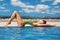 Young adult attractive woman in swimsuite relaxing on rooftop pool edge with blue sky and mountains on background. Beautiful sexy