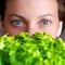 Young adult beautiful caucasian happy smiling woman portrait holding green fresh lettuce salad crop in front face. Healthy food