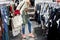 Young adult beautiful woman choosing clothes at market or retail clothing store in mall indoors. Sale discount season at fashion