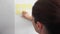 Young adult business woman placing a sticky notes on a wall