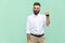 Young adult businessman has an idea, pointing with finger up isolated on light green wall background.