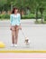 Young adult caucasian pretty woman crossing street on crosswalk with small dog jack russel terrier at summer day. Female