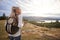 A young adult Caucasian woman standing alone on the hill during hiking, admiring view, back view