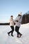 Young adult couple cheerfully flounders in snowy forest. Comic fight. Happy young couple hugs in winter