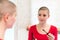 Young adult female cancer patient with gorgeous new short hair, looking in the mirror, applying mascara.