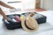 Young adult female packing luggage for summer vacation. woman tourist checking list travel accessories in suitcase on the bed.