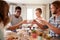 Young adult friends passing a dish across the dinner table at lunch, close up