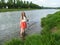 Young adult girl with long blond hair knee-deep in water and looks at the camera