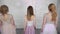 Young adult girls go around the white room with their backs and turn to camera.