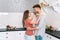Young adult husband and wife dancing on kitchen
