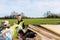 A young adult male builder wearing a high visibility vest throwing rubbish into a skip