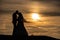 Young adult male groom and female bride holding hands on beach at sunset.