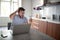 Young adult man with beard and tattoo wearing glasses, yawns, looking his cell phone, in front of laptop on table. lifestyle,