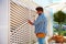 Young adult man decorating the house wall, by setting up the wooden trellis for climbing plants