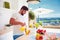 Young adult man, father pouring fresh juice while standing in open space kitchen on a sunny summer day