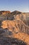 Young adult man flying drone in semi-desert area with erosional figures and cliff