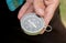 Young adult man holding a simple compass in hand outdoors, object detail, extreme closeup. Finding the right direction, seeking,