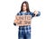 Young adult man with long hair holding united we stand banner with angry face, negative sign showing dislike with thumbs down,