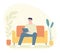 Young adult man sitting on orange sofa using tablet indoors. Relaxed male with digital device at home. Comfortable