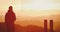 Young adult man, traveller walking along the trail with the orange mountain ranges on the background at sunrise