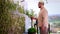 Young adult man watering the ivy vertical wall at the rooftop garden on summer day