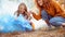 Young adult mother and daughter looking at carved pumpkin with smoke