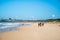 Young adult surfers in wetsuits carrying surfboards on a sandy beach