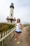 Young adult tourist poses by Pigeon Point Lighthouse along the California Coastline with hands on hips