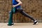 Young adult white woman exercising outdoors with resistance band in front of brick wall