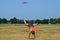 Young adult woman attempts to do a cartwheel in a park, but fails. Airplane and Washington Monument in the background