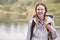 Young adult woman on a camping holiday standing by a lake laughing, portrait, Lake District, UK